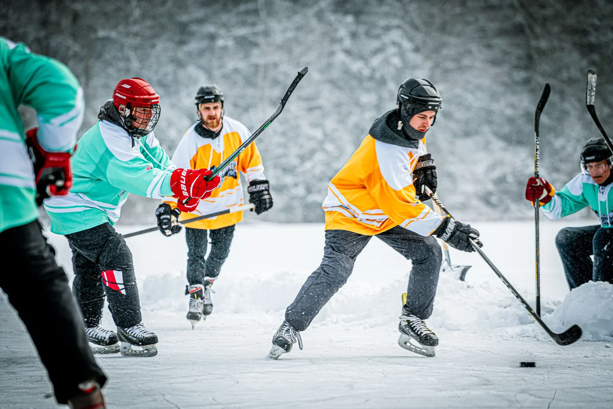 Hockey players competing outdoors in the snow at the Berkshire Pond Hockey Classic
